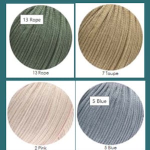 May include: Four balls of yarn in different colours: green, beige, pink, and blue. The yarn is labelled with numbers and colour names: 13 Rope, 7 Taupe, 2 Pink, and 5 Blue.