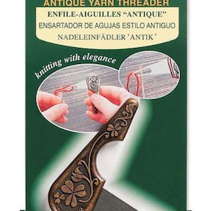 May include: An antique yarn threader on a green and white package. The threader is bronze-colored with a clover design and the text "Clover." The package also includes the text "Antique Yarn Threader" in multiple languages and "knitting with elegance."