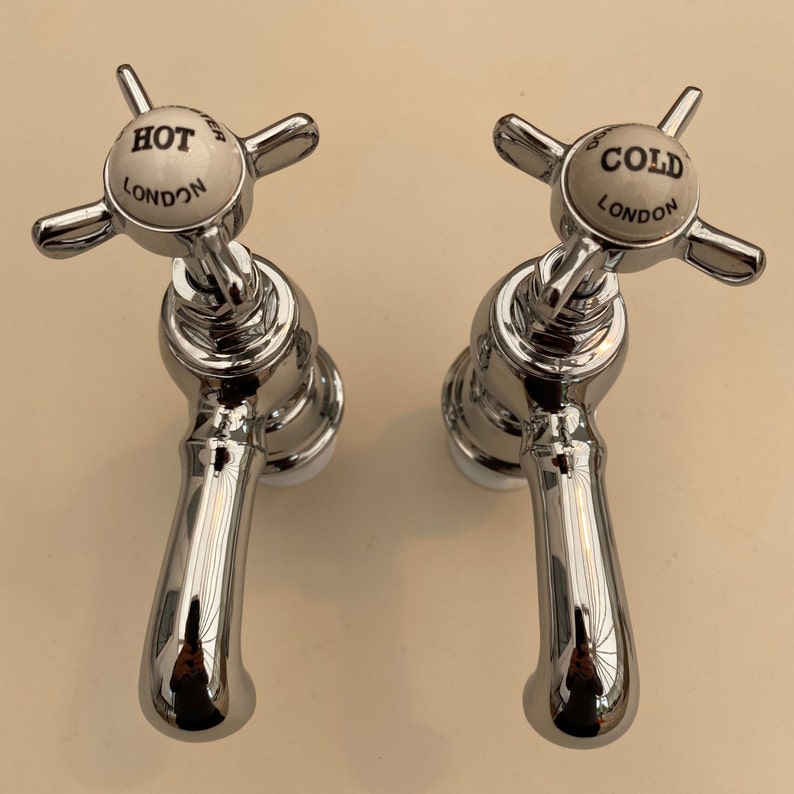 Puede incluir: Dos grifos de ba&ntilde;o cromados con manijas de porcelana. Las manijas est&aacute;n marcadas con "HOT LONDON" y "COLD LONDON".