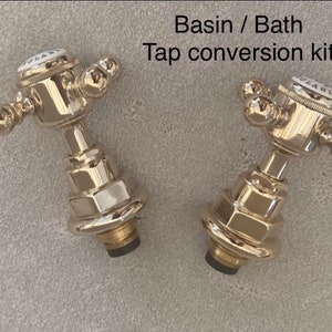 May include: Two chrome tap conversion kits for a basin or bath. Each kit features a round, chrome tap handle with a white ceramic knob that says "GLAND".