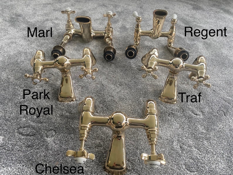 May include: Several gold-colored bathroom faucets are displayed, each with a unique design. The faucets have cross-shaped handles and are labeled with names like "Marl," "Regent," and "Chelsea." The image is taken from a top-down perspective.
