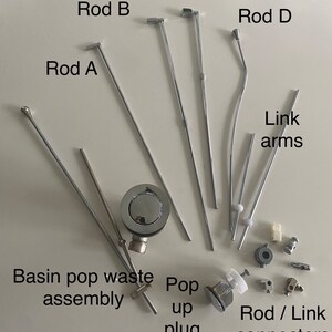 May include: A set of chrome-plated pop-up rods, a pop-up plug, and connecting hardware for a bathroom sink. The rods are labeled "Rod A", "Rod B", "Rod C", and "Rod D". The hardware is labeled "Link arms" and "Rod / Link connectors".
