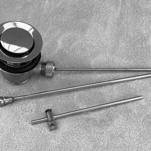 Puede incluir: Un tap&oacute;n de desag&uuml;e de ba&ntilde;era cromado con una tapa redonda y una varilla de metal larga y delgada cromada.