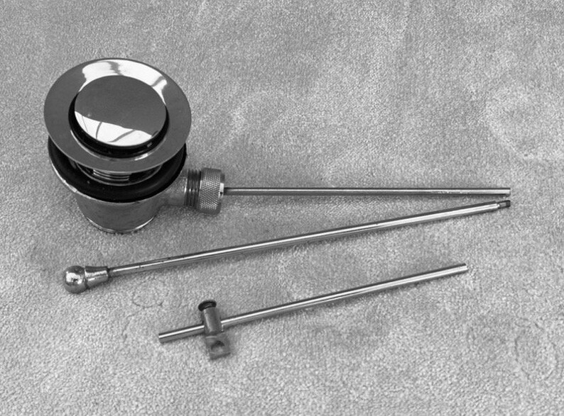 Puede incluir: Un tap&oacute;n de desag&uuml;e de ba&ntilde;era cromado con una tapa redonda y una varilla de metal larga y delgada cromada.