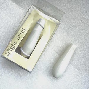 May include: A light pull, a cylindrical object with a rounded end, is shown in its original packaging. The packaging is clear plastic with a yellow backing. The text "Light Pull" is printed on the packaging.