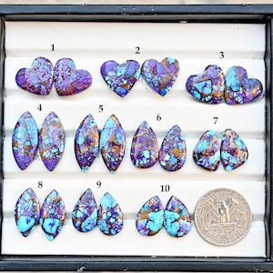 May include: A collection of ten gemstone pairs in various shapes, including hearts, ovals, and teardrops. The stones feature a mix of purple, turquoise, and gold colors. A US quarter is included for size reference.