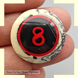 Könnte beinhalten: Eine schwarze und weiße Billardkugel mit einer roten Acht darauf. Die Kugel hat ein marmoriertes Muster.