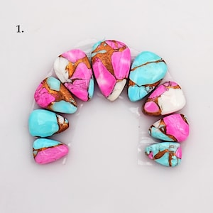 May include: A selection of polished gemstone cabochons in various shapes. The stones display a mix of colours, including pink, turquoise, white, and copper-coloured matrix patterns. The arrangement is on a white surface.
