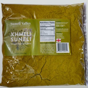 May include: A large bag of yellow-brown Khmeli Suneli Georgian Style Spice Blend, a product of Georgia, with a nutrition facts label and ingredients list. The bag is labeled with the brand name Suneli Valley and has a net weight of 2.22 lb (1 kg).