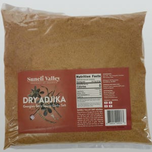 May include: A resealable bag of brown dry adjika spice blend, a Georgian-style spicy garlic salt. The bag is labeled "Suneli Valley Dry Adjika" and includes a nutrition facts label and ingredients list. The bag is on a white background.
