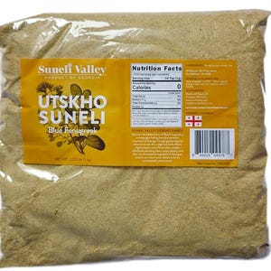 May include: A clear plastic bag filled with a light brown powder. A yellow label reads "Utskho Suneli Blue Fenugreek" with nutritional information and a barcode. Net weight is 2.22 lbs (1 kg).