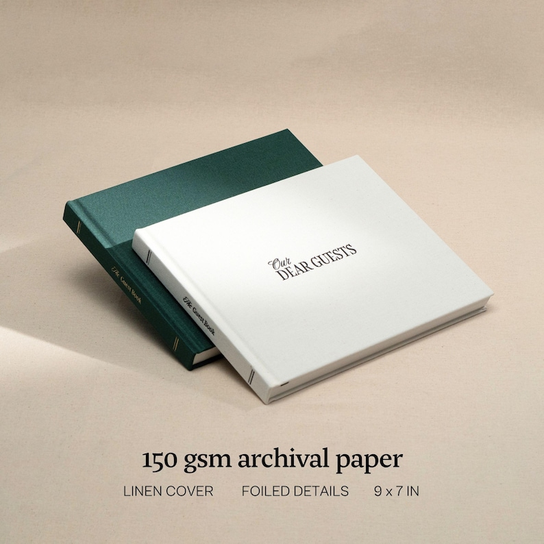 May include: Two guest books, one green and one white, are displayed. The white book, with the text "Our Dear Guests," is on top. The books are 9 x 7 inches and have linen covers and foiled details. The paper is 150 gsm archival.
