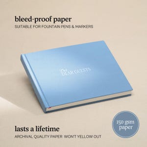 May include: A light blue guest book with the words "Our Dear Guests" in white script. The book has a hard cover and is labeled as bleed-proof paper suitable for fountain pens and markers. The book is made with archival quality paper that won't yellow out.