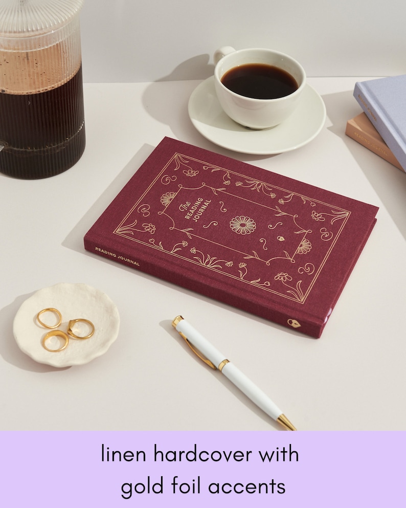 May include: A burgundy linen hardcover journal with gold foil accents and the text "The Reading Journal" on the front cover.