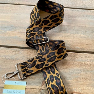 May include: A leopard print bag strap with silver-tone metal hardware. The strap is a mix of brown and tan colors. The tag reads "Rose & Rose Boutique".