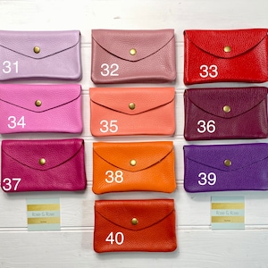 May include: A collection of ten leather wallets in various colors, including lavender, pink, red, and orange. Each wallet has a flap closure with a gold-colored snap. The wallets are numbered from 31 to 40.