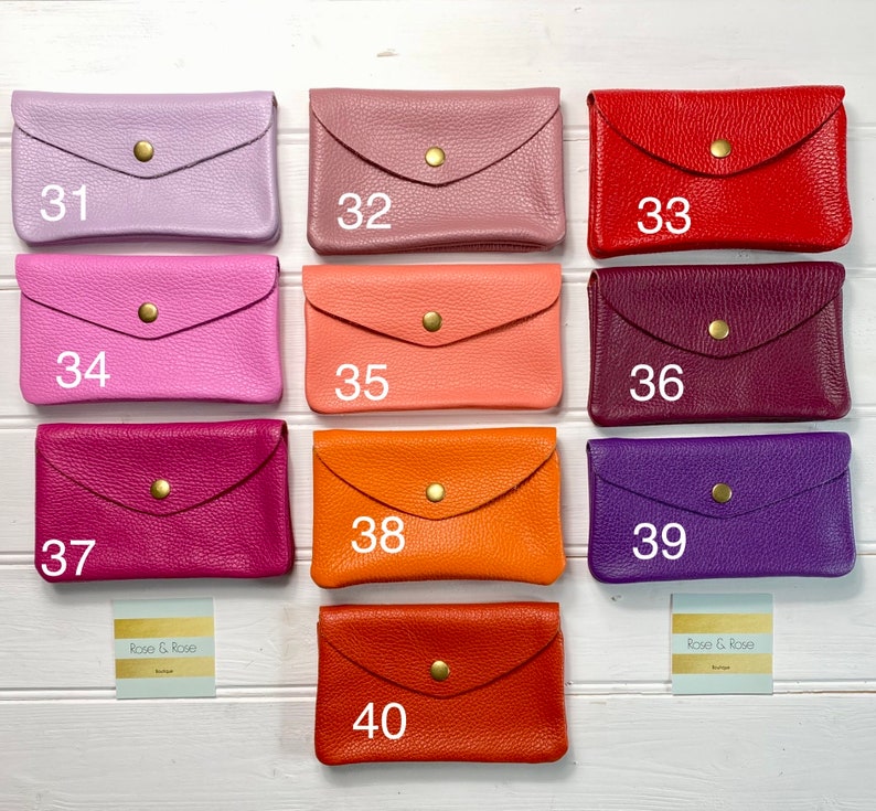 May include: A collection of ten leather wallets in various colors, including lavender, pink, red, and orange. Each wallet has a flap closure with a gold-colored snap. The wallets are numbered from 31 to 40.