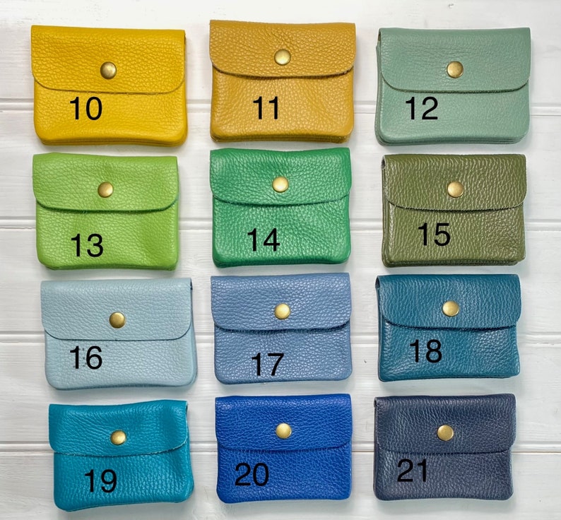 May include: A collection of small, leather coin purses in various colors, including yellow, green, blue, and teal. Each purse has a flap closure with a gold-colored snap. Numbers 10 through 21 are printed on the purses.