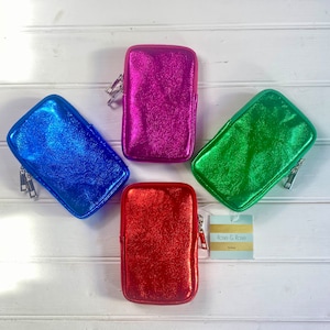 May include: Four metallic zippered pouches in blue, magenta, green, and red. Each pouch has a silver zipper and a small loop. A tag with the text "Rose & Rose" is also visible.
