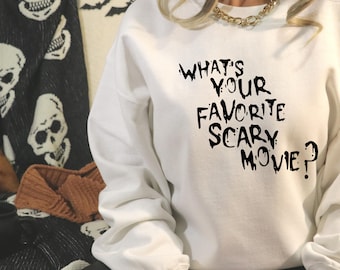 May include: White sweatshirt with black dripping text that reads "What's Your Favorite Scary Movie?"