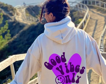May include: A white hoodie with a purple heart graphic on the back. The heart has the text "Good Vibes Only" inside of it.
