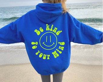 May include: A royal blue hoodie with a bright yellow smiley face and the text "Be kind to your mind" in a retro font.