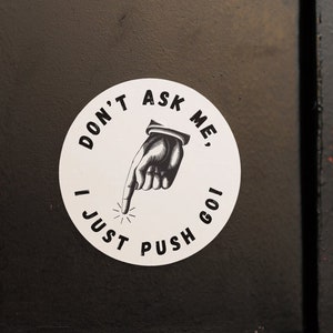May include: A white sticker with black text and a black hand pointing to the right. The sticker says "Don't ask me, I just push goo!"
