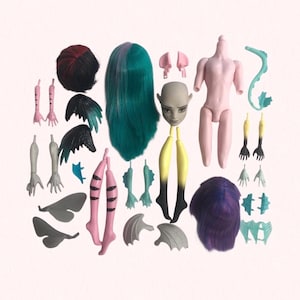 May include: A collection of doll parts, including a nude torso, heads, hair, limbs, wings, and fins. The hair pieces are in various colors, including teal, purple, and black with red highlights. The limbs and wings are in shades of pink, gray, and black.