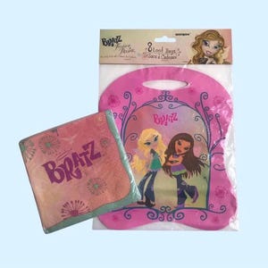 May include: Pink and green party favor bags with the text "Bratz Fashion Pixies" and "8 Loot Bags Sacs a Cadeaux" on the front. The bags feature a pink and white design with a floral pattern and images of Bratz dolls.