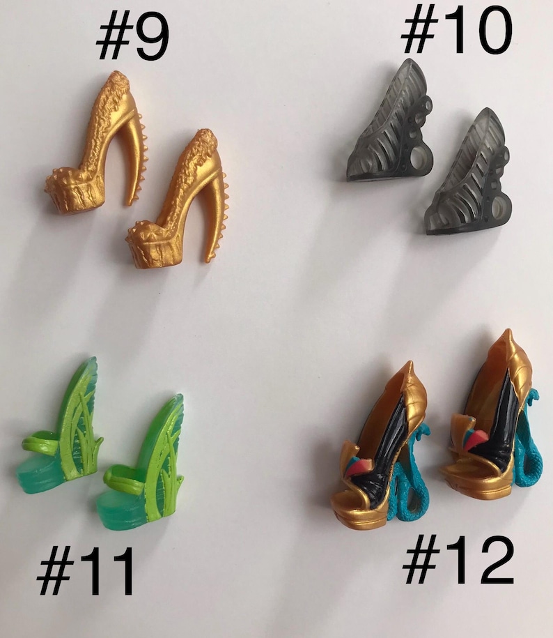 May include: Four pairs of miniature doll shoes labeled #9 through #12. Pair #9 are gold platform heels with textured details. Pair #10 are translucent grey cutout heels. Pair #11 are green leaf-themed platform sandals. Pair #12 are gold and black heels with blue snake-shaped heels.