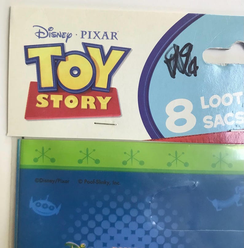 Puede incluir: Un paquete de la marca Disney Pixar Toy Story que contiene 8 bolsas de regalo. El empaque presenta el logotipo de Toy Story en amarillo y rojo sobre un fondo crema, con detalles y texto en azul. Debajo, un panel azul y verde muestra el logo.
