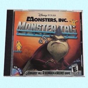 May include: A Monsters, Inc. Monster Tag CD-ROM game case. The cover features a purple monster wearing glasses, with the game title in large letters. The case is in a clear plastic sleeve.