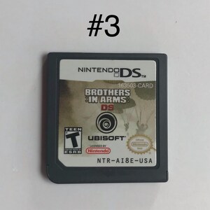 Op de afbeelding: Grijze Nintendo DS-gamecartridge voor "Brothers in Arms: DS". De cartridge toont het Nintendo DS-logo, het Ubisoft-logo en de ESRB-classificatie. De titel van het spel is duidelijk zichtbaar.