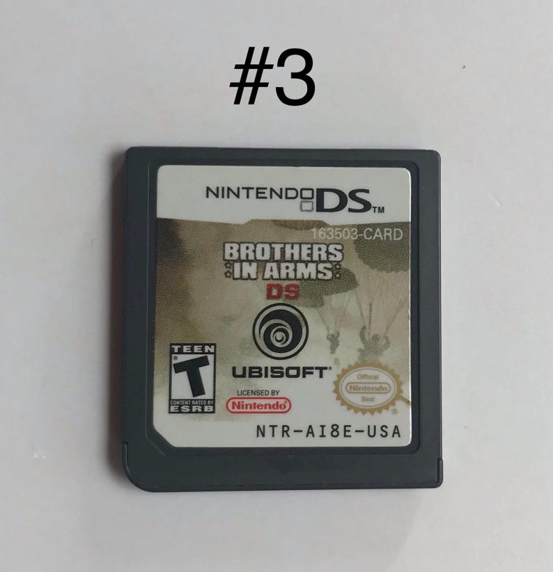 Op de afbeelding: Grijze Nintendo DS-gamecartridge voor "Brothers in Arms: DS". De cartridge toont het Nintendo DS-logo, het Ubisoft-logo en de ESRB-classificatie. De titel van het spel is duidelijk zichtbaar.