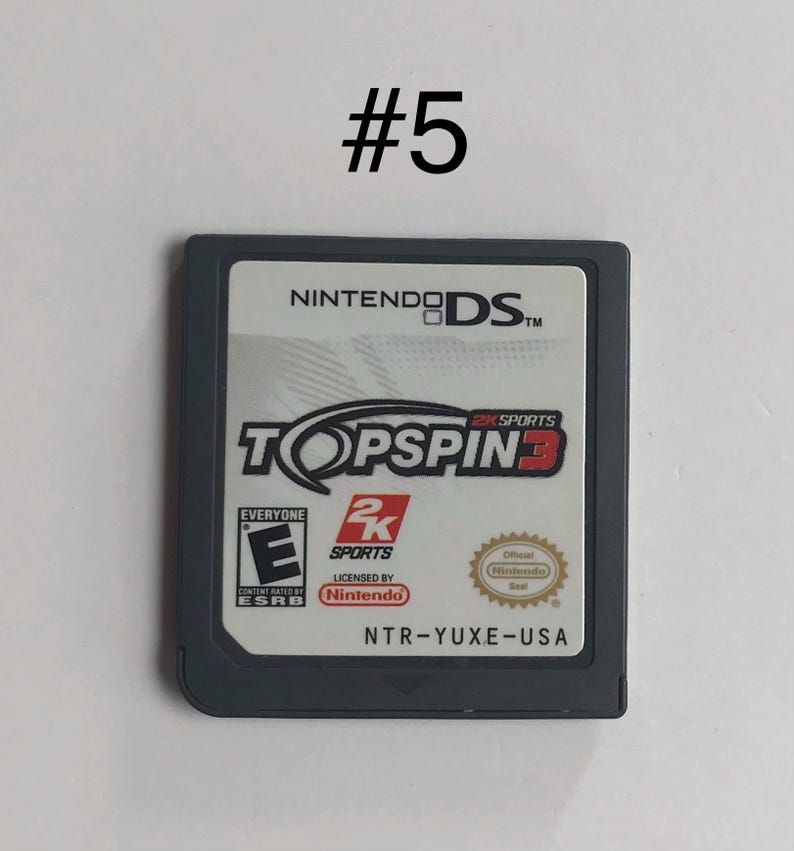 Op de afbeelding: Een Nintendo DS-gamecartridge voor Top Spin 3. De gamecartridge is donkergrijs met een wit label met de titel van de game, de ESRB-classificatie en het Nintendo-merk. De cartridge is genummerd 5.
