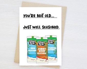 May include: A greeting card with the text "You're not old... Just well seasoned." featuring illustrations of three Dunn's River seasoning containers. The containers are labeled "Jerk Seasoning", "Curry Goat Seasoning", and "Purpose Seasoning".