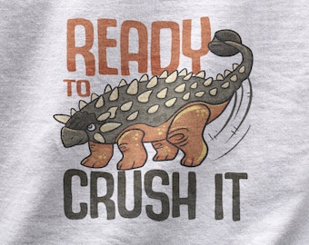 May include: A grey t-shirt with a cartoon illustration of an Ankylosaurus dinosaur with the text "Ready to Crush It".