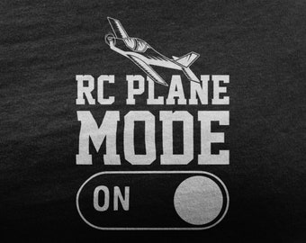 May include: A black t-shirt with a white graphic of a small airplane, the text "RC PLANE MODE ON" and a white toggle switch.