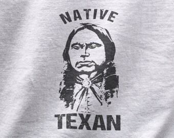 May include: A grey t-shirt with a black and white image of a Native American man with the text "NATIVE TEXAN" printed on it.