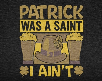 Puede incluir: Una camiseta negra con un diseño gráfico amarillo que dice "Patrick era un santo, yo no". El gráfico también incluye dos vasos de cerveza y un sombrero de duende con tréboles.