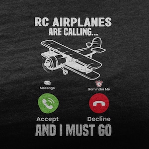 Puede incluir: Camiseta gris oscuro con texto y gráficos blancos. El texto dice "RC AIRPLANES ARE CALLING..." encima de un gráfico de un biplano. Debajo del avión hay iconos de teléfono con las palabras "Aceptar" y "Rechazar". El texto "AND I MUST GO" está en la parte inferior.