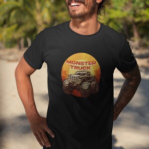 Puede incluir: Una camiseta negra con un gr&aacute;fico de estilo vintage de un cami&oacute;n monstruo frente a una puesta de sol. El texto "Monster Truck" est&aacute; impreso en rojo sobre el cami&oacute;n.