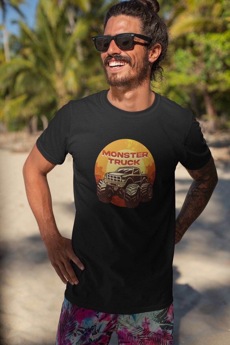 Puede incluir: Una camiseta negra con un gr&aacute;fico de estilo vintage de un cami&oacute;n monstruo frente a una puesta de sol. El texto "Monster Truck" est&aacute; impreso en rojo sobre el cami&oacute;n.