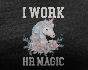 May include: A black t-shirt with white text that reads "I work HR magic". A white unicorn with a pink horn and floral accents is centered on the shirt.