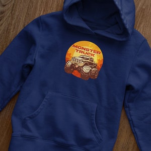 Puede incluir: Una sudadera con capucha azul marino con un bolsillo en la parte delantera. La sudadera tiene un gr&aacute;fico de un cami&oacute;n monstruo con el texto "Monster Truck" en un c&iacute;rculo.