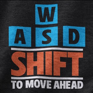 May include: A black t-shirt with the letters "WASD" and "SHIFT" in blue and orange squares, with the text "TO MOVE AHEAD" below.