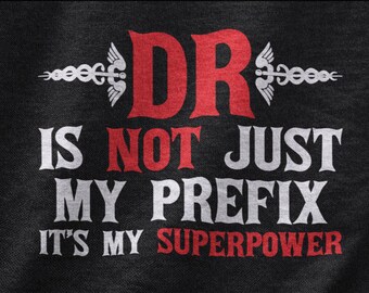 May include: Black and white text on a black background reads "DR is not just my prefix it's my superpower". The text is stylized with a vintage font. Two red medical caduceus symbols flank the word "DR".