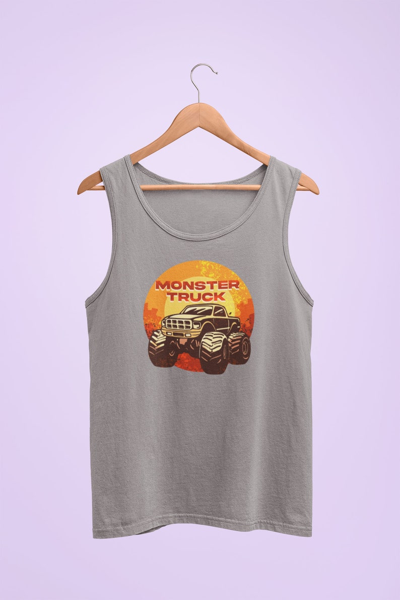 Puede incluir: Una camiseta sin mangas gris con un gr&aacute;fico de un cami&oacute;n monstruo en una puesta de sol. El texto "Monster Truck" est&aacute; impreso en rojo sobre el cami&oacute;n.