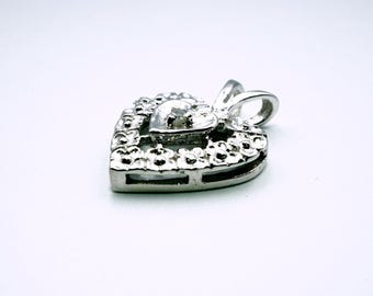 May include: A silver heart-shaped pendant with a smaller heart in the center. The pendant is decorated with small, raised dots around the edges.