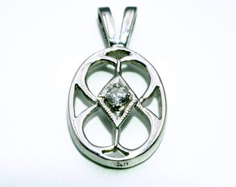 May include: A silver pendant with a diamond in the center. The pendant is in the shape of a circle with a geometric design.